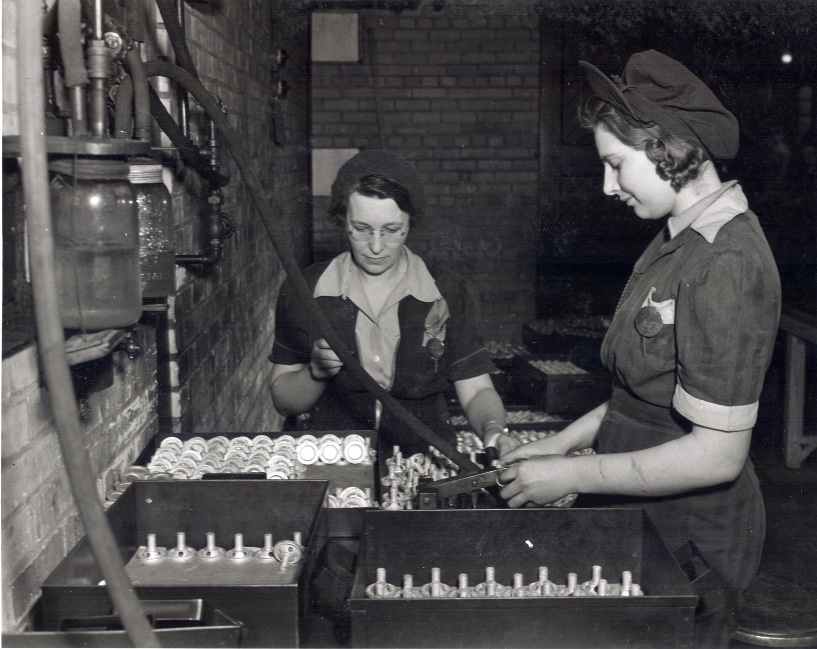 Employees Margaret MacLeod (left) and Bernice Keller (right) testing 2 inch smoke bomb adapters. Courtesy the Waterloo Public Library.