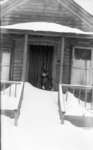 Middle Island:  Esther Hartlep with stuffed bear on snow-drifted porch of dwelling.