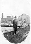 042 Man standing in front of logs at a lumber mill