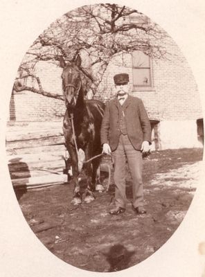 069 Unidentified man with horse in front of large brick building