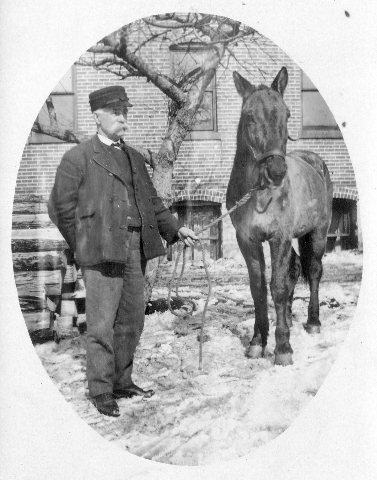 069 Unidentified man with horse in front of large brick building