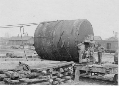 150 Three men posing with very large cylindrical metal “drum”