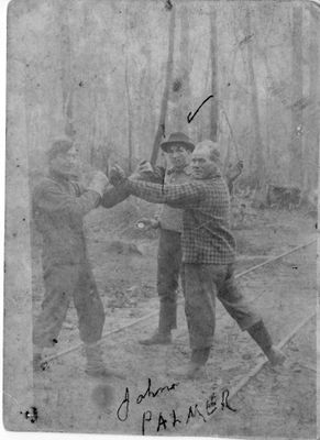 449 Three lumbermen “boxing” along railway line in woods.