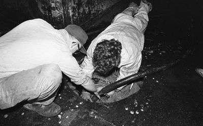 Two people removing oil from the NORDMEER wreck