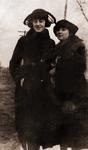 “Viola Baird Daughter of Bob Baird” “Ruby Wylie (left)”. Ruby and Viola stand close to each other in long coats and scarves. Telephone pole in the background.