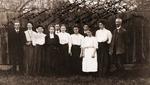 Group of 11 Men and Women Posing in Front of a Fence