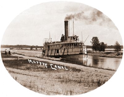 Steamship on the Murrey Canal (spelling on post card). There are two women and a dog watching the ship go by.