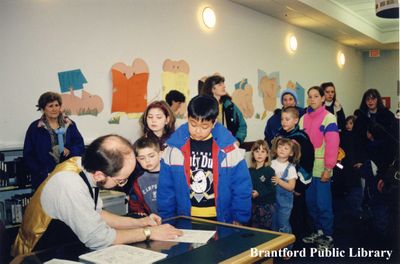 Magician Peter Mennie Signs Autographs for a Group of Children at the Brantford Public Library