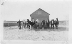 Art Brame and 8 draft horses with a frame building, Saskatchewan, 1923
