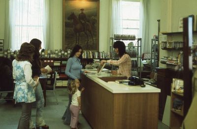 Interior of Carnegie library, checkout desk and film department, 1975