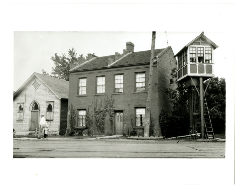 1997.37.1 <b>Charity Block</b><br>
Rue King est, Chatham, le James Charity Block <br> 
avec le point de vue du chemin de fer et l'église<br>épiscopale méthodiste africaine (démoli environ 1950s)<br>