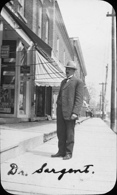 Dr. W.A. Sargent on a King Street East storefront sidewalk, Colborne