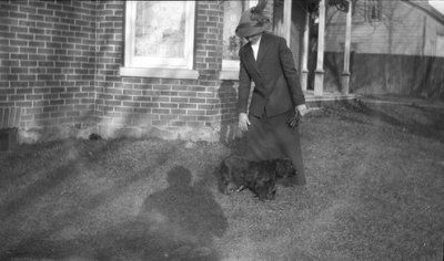 Woman standing in front of a home with her dog