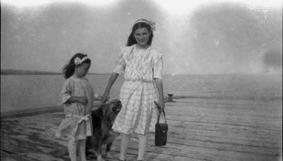 Two young girls and a dog on a wharf