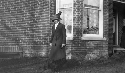 A woman standing in front of a brick Ontario cottage, Gothic Revival