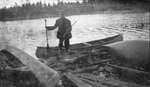 Man with a slain stag at his feet standing at the water's edge