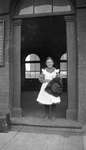 A young girl holding her hat in the doorway of the Grand Truck Railroad Station