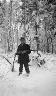 A man holding a rifle in a winter hunting camp