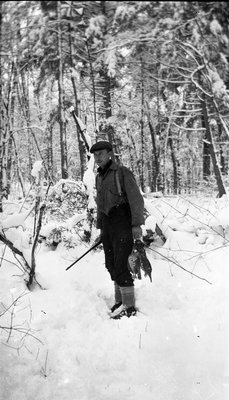 A hunter holding pheasant, winter scene