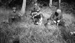 A hunting party and a dog in a field