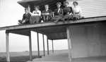 A group of women and men sitting on the edge of a porch roof