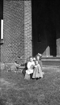 Three little girls in front of a brick house