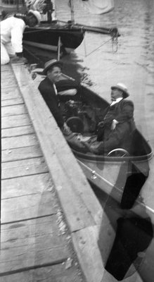 Two men in a boat at a wharf