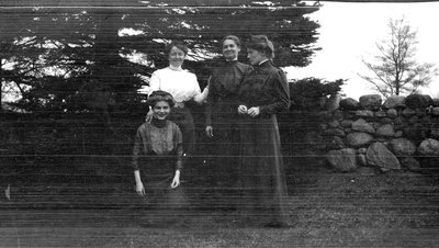 A group of women posing in front of a stone wall, possibly Victoria Beach Road, Colborne