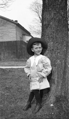 A young boy posing under a tree