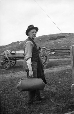 A man holding a pipe and a bag, possibly a doctor's bag