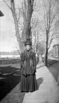 A woman standing on a Church St. West wooden sidewalk, Colborne