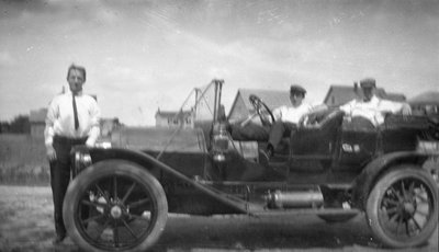 Three men posing with a 1910s car