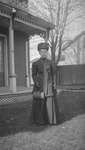 A woman in formal dress standing in front of a house