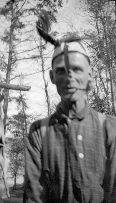 A hunter smoking a pipe and wearing a hat with feathers