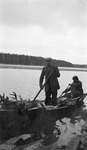 Two deer hunters transporting a load of slain deer by boat