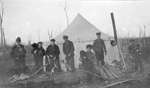 A group of hunters with their dogs resting at camp