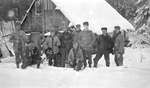 A group of deer hunters posing outside of their camp