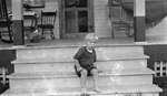 A young boy sitting on the steps of the Griffis' summer home