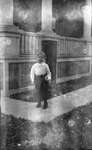 A young Griffis? boy standing outside in front of a house