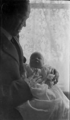 Frank Griffis and baby in front of a window