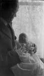 Frank Griffis and baby in front of a window