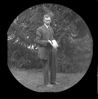 A man standing in front of a large pine tree