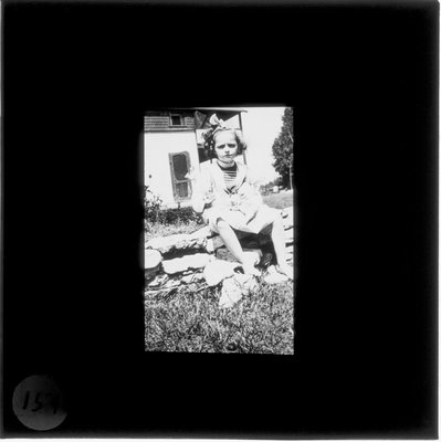 A young girl holding a cat as her grandmother stands a doorway