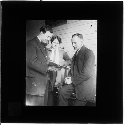 A woman and two men looking at a book