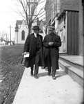 Two men walking along a sidewalk with the Colborne Methodist Church, now Colborne Pastoral Charge of the United Church in the background