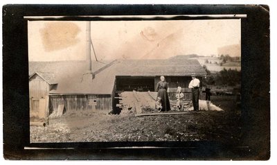 Group photograph of an elderly couple and two children in front of a barn