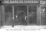 Charlie Eddy with two unidentified men in front of the Bank of Toronto and Chase Brothers Company, Colborne, Cramahe Township, May 11 1910