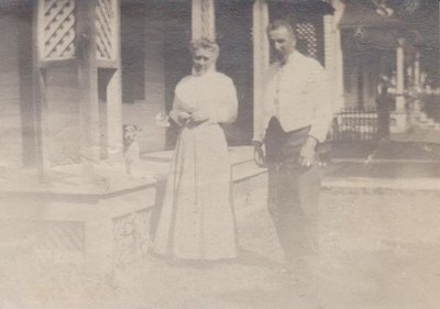 Man and a woman with a dog in front of a house