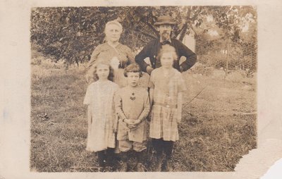 Postcard of grandparents and grandchildren after picking apples