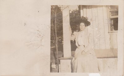 Postcard of Beatrice, a young woman, sitting on a porch, 1908